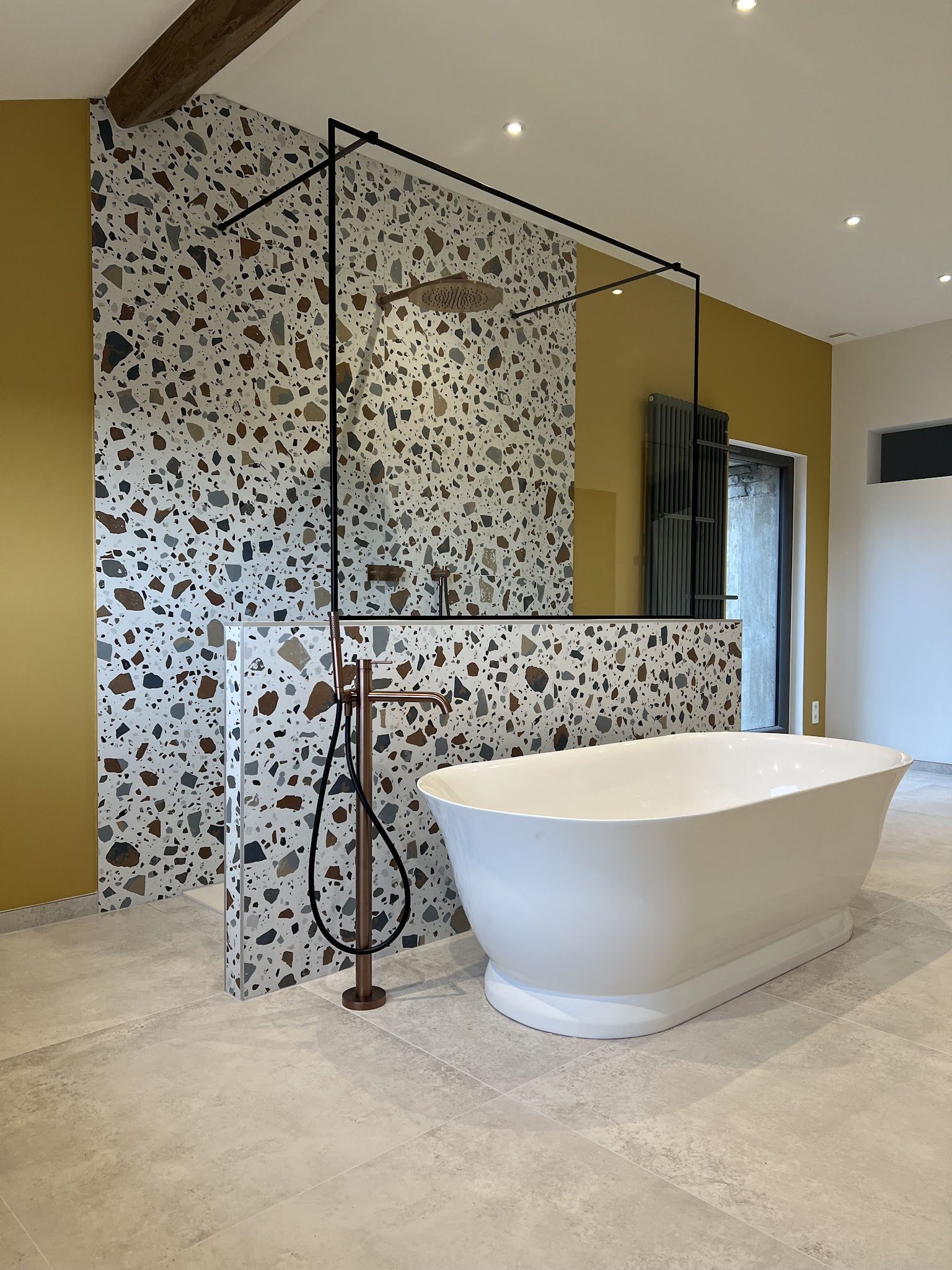 Salle de bains clé en main avec terrazzo, mur moutarde et baignoire îlot