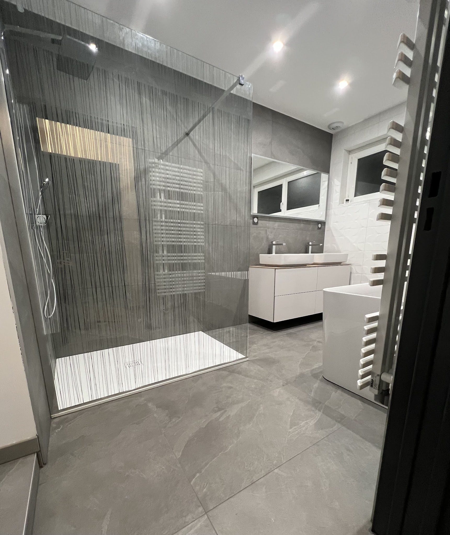 Douche à l'italienne en grand format gris avec paroi vitrée